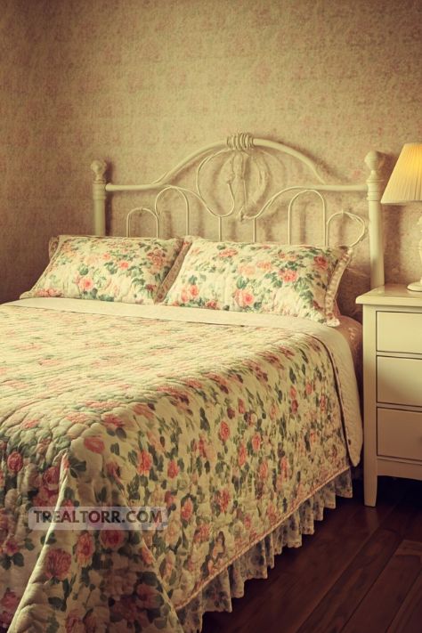 A vintage bedroom with floral bedding, including a quilt with soft pastel flowers, creating a warm and nostalgic vibe.