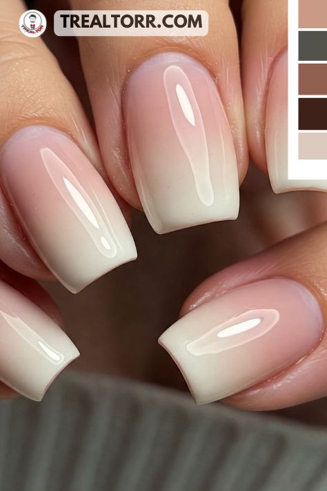 A close-up of nude ombre nails transitioning from a soft beige to a pale pink, with a shiny finish, creating a smooth, elegant look