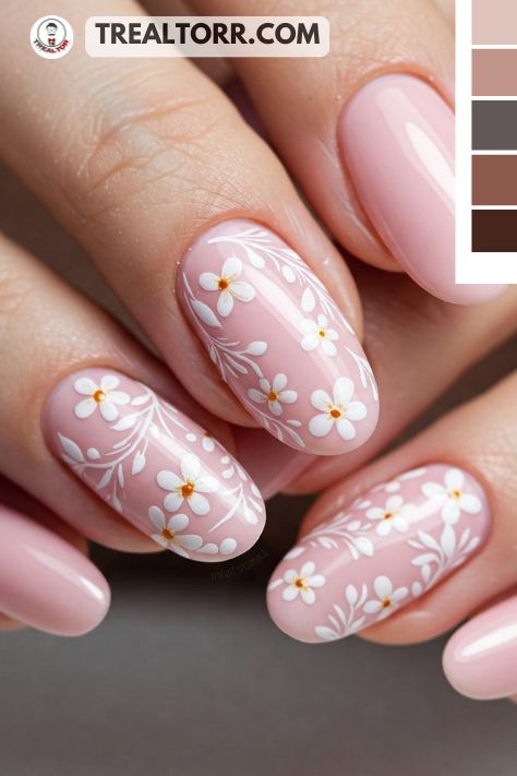 A set of nails with a soft pink base and delicate white floral nail art designs, creating a fresh and feminine look