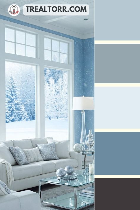 A cozy living room with frosted blue walls, white furniture, and silver accents, resembling a winter wonderland.
