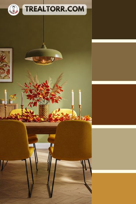 A dining room with olive green walls, mustard yellow chairs, and a wooden table decorated with a centerpiece of fall foliage.